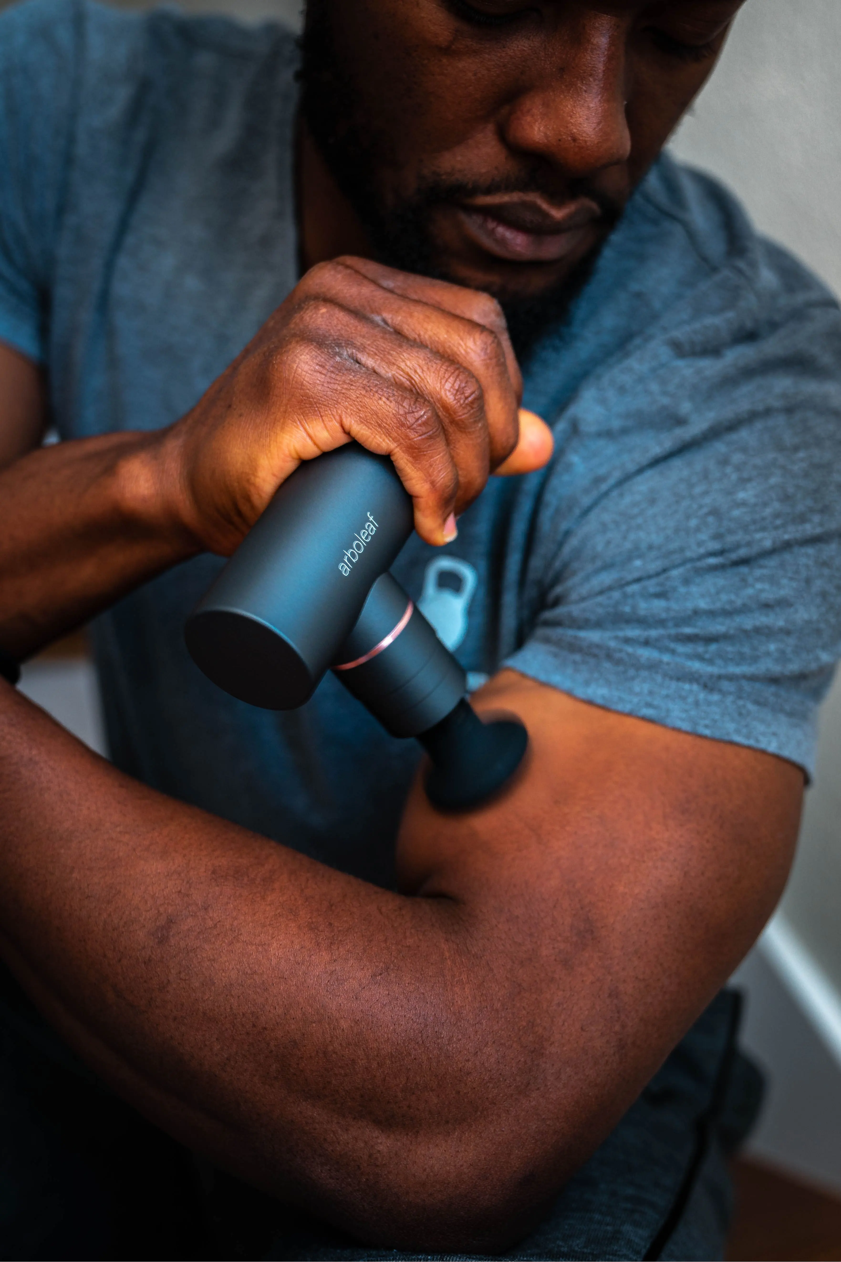 man using Arboleaf massage gun to relax arm muscles