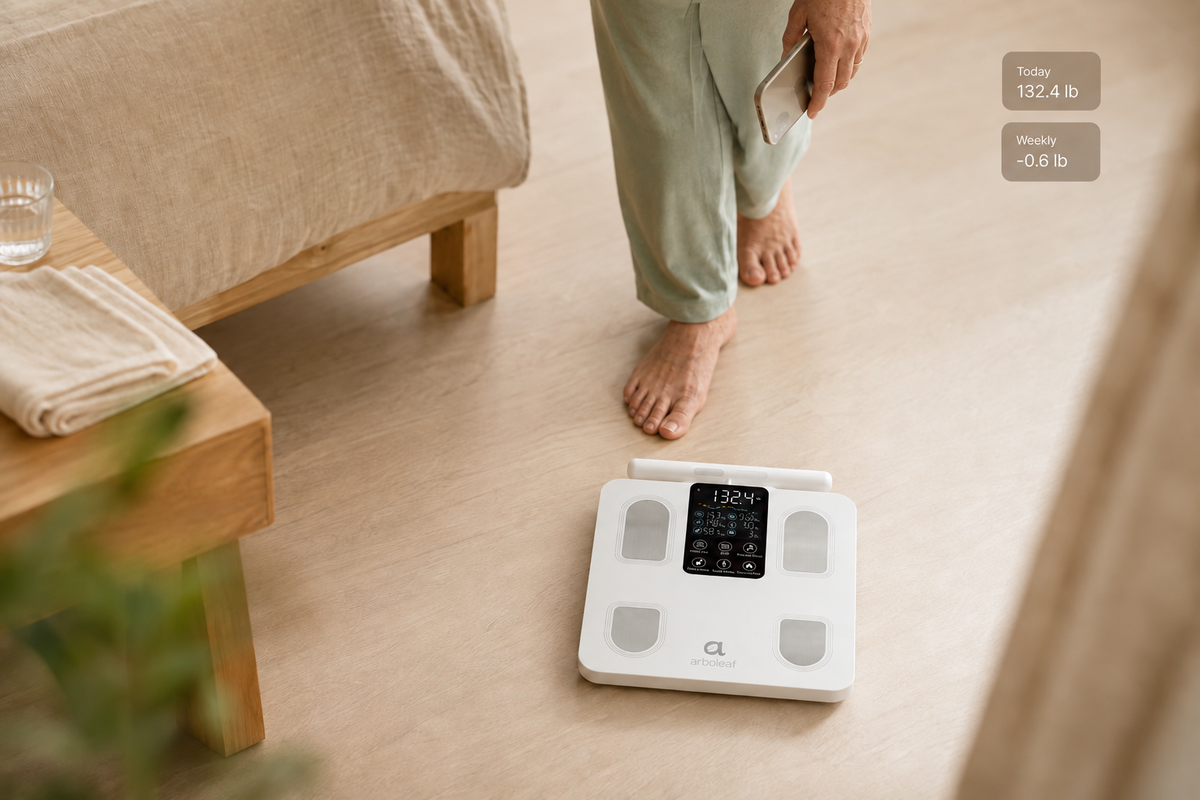 Older Japanese adult approaching an Arboleaf white smart scale at home