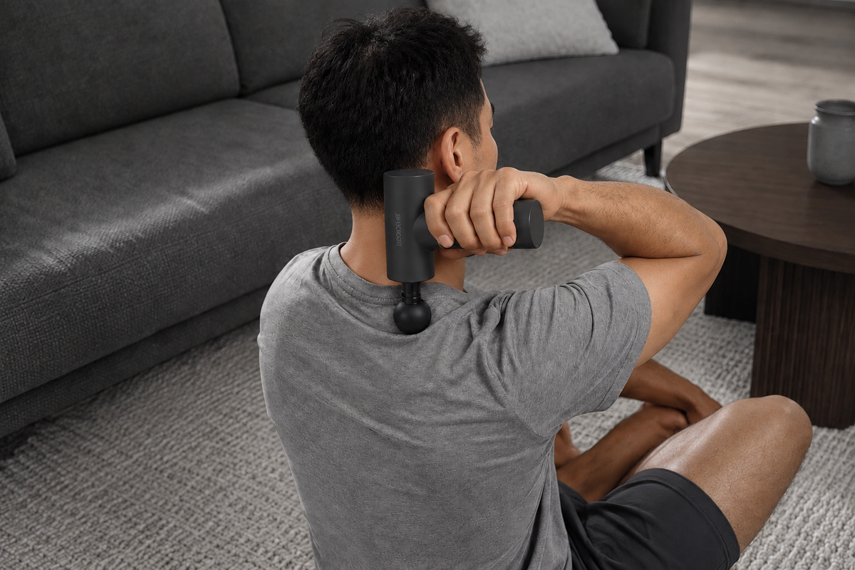 Japanese man using an Arboleaf massage gun at home